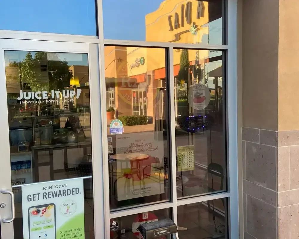 The front window of a juice and smoothie shop with the name 'Juice It Up!' visible. The windows look freshly cleaned and very good.