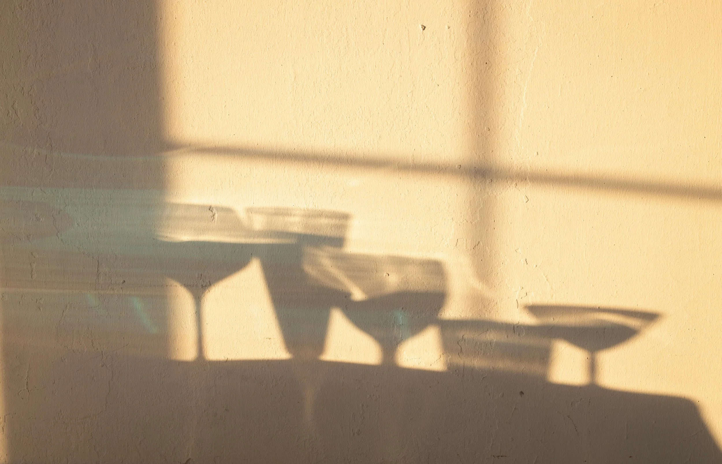 Shadow play of champagne and martini glasses against a wall — modern wedding styling aesthetic