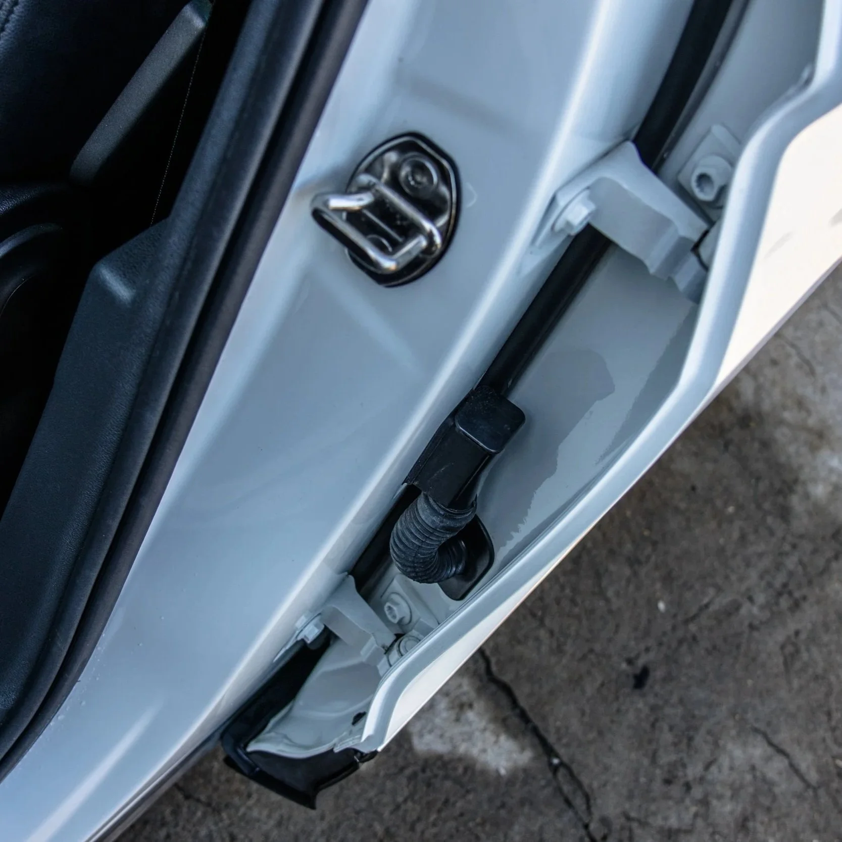 Close-up of the door latch mechanism and a black wiring conduit inside a vehicle door.