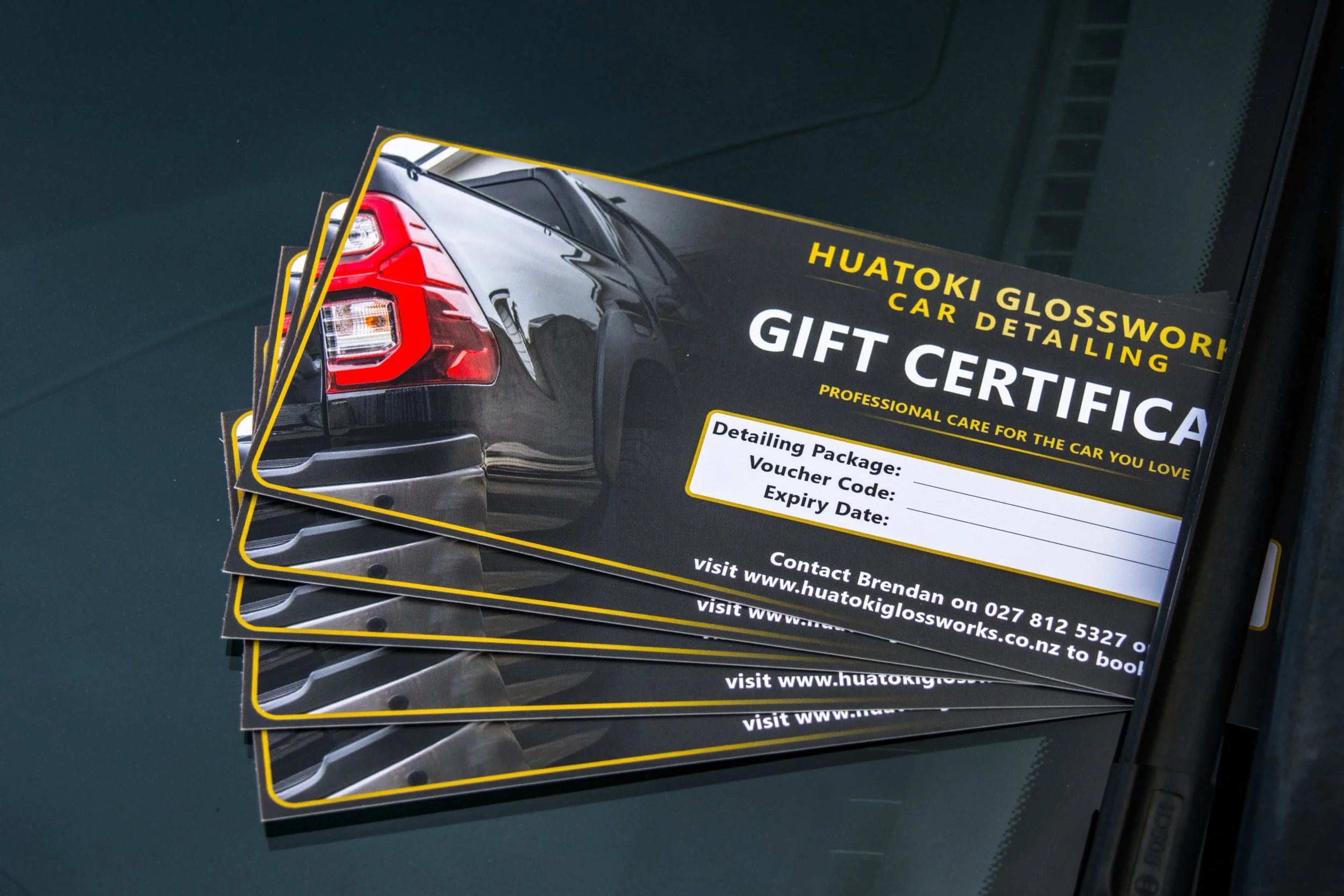 Stack of gift certificates for Huatoki Glosswork with a close-up of a black car's rear light on the cover.