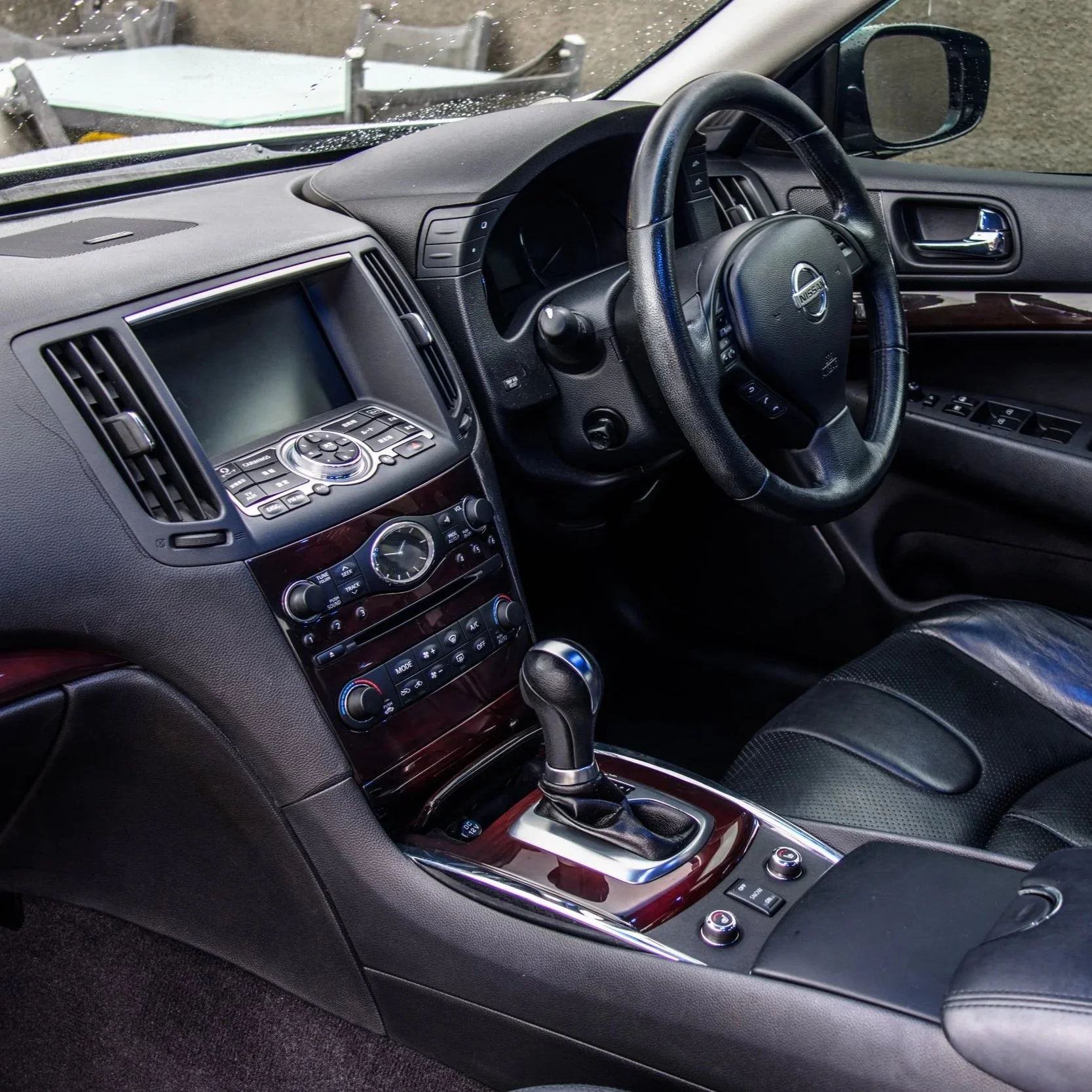 Interior view of a black Nissan car, showing the dashboard, steering wheel, gear shift, and front passenger seat.