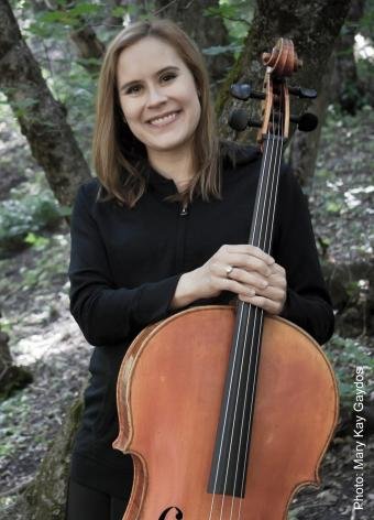 Young woman holding a cello outdoors in a forest