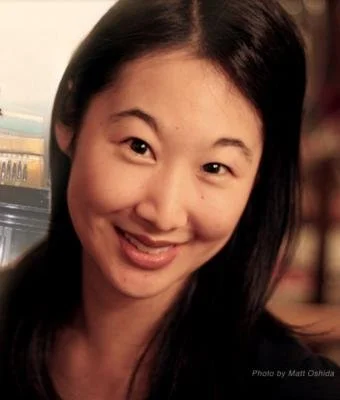 A smiling woman with long black hair and a light complexion