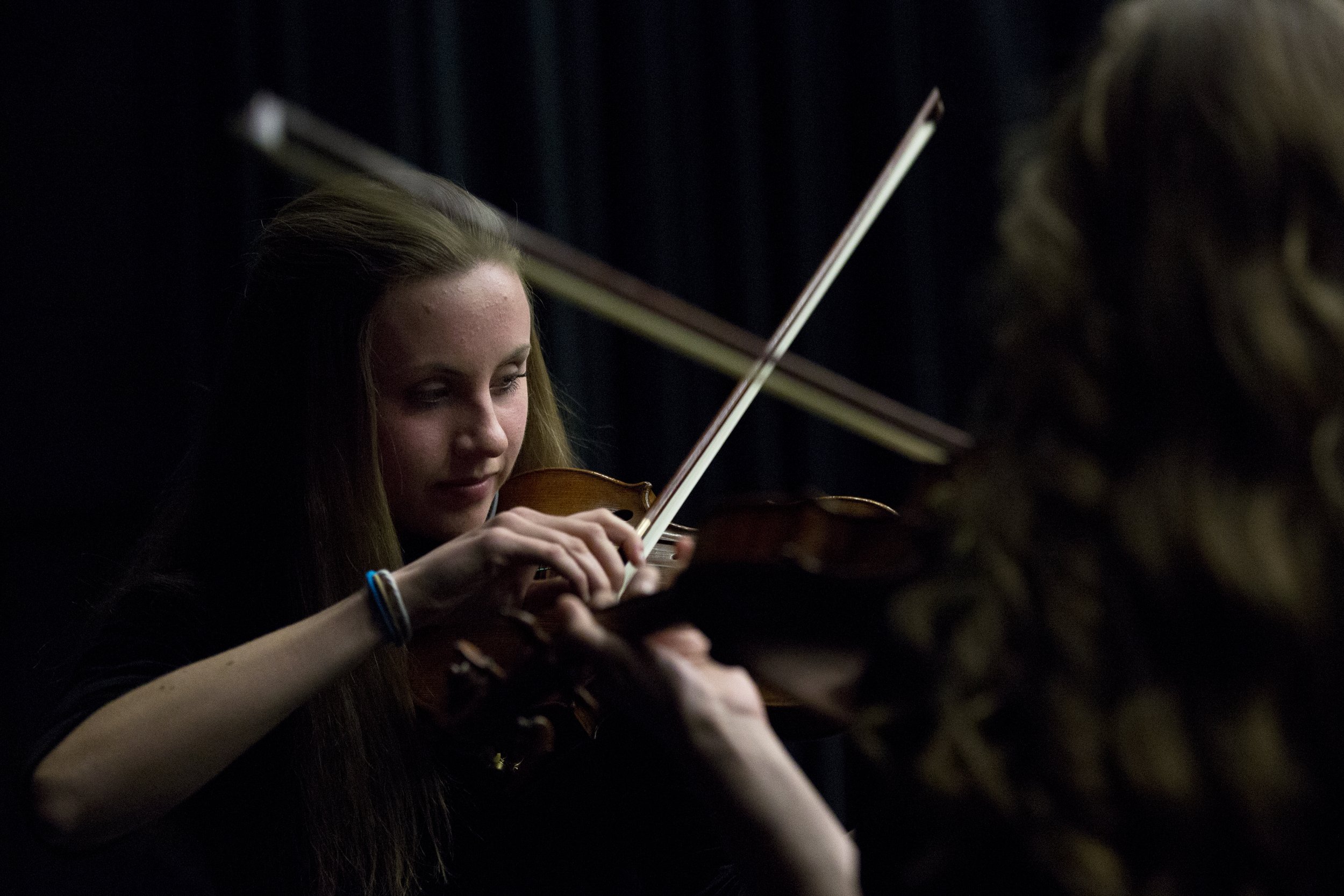 Young woman playing the violin in a dark setting.