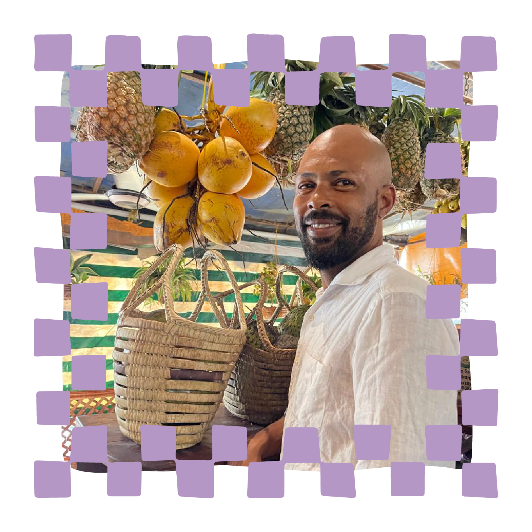 A man smiling at a coconut farm with bunches of ripe coconuts hanging from trees and woven baskets in the foreground.