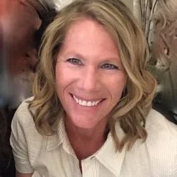A woman with blonde hair and a white shirt smiling at the camera.