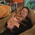 Person lying on a couch holding a small dog