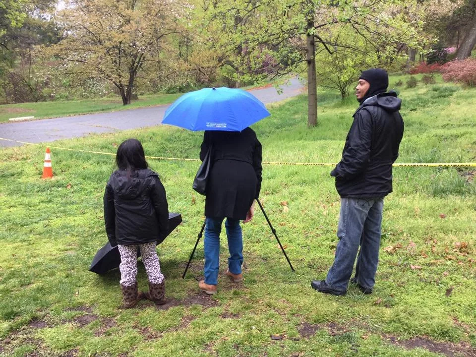 Rain changes the conditions, not the commitment; the watch continues beneath an umbrella.