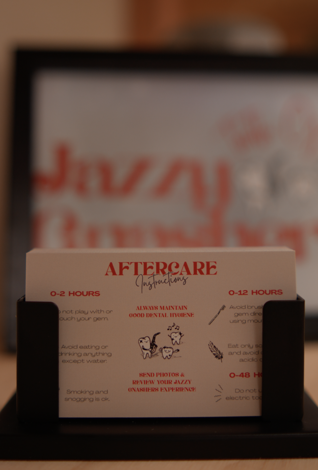 A dental aftercare instruction card in a black holder with red and black text, illustrations of teeth with a toothbrush and musical notes, and tips for dental hygiene after procedures.