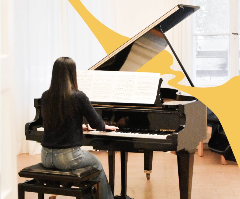 Ein junger Mann spielt Klavier in einem Raum mit weißen Wänden.