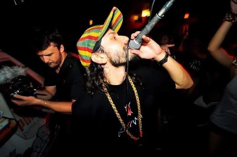 A man singing in a club and a DJ operating music equipment