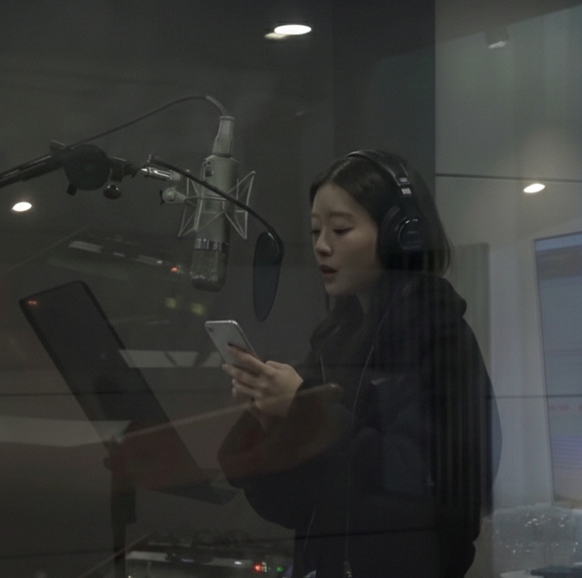 Woman with headphones reading from a smartphone in recording studio.
