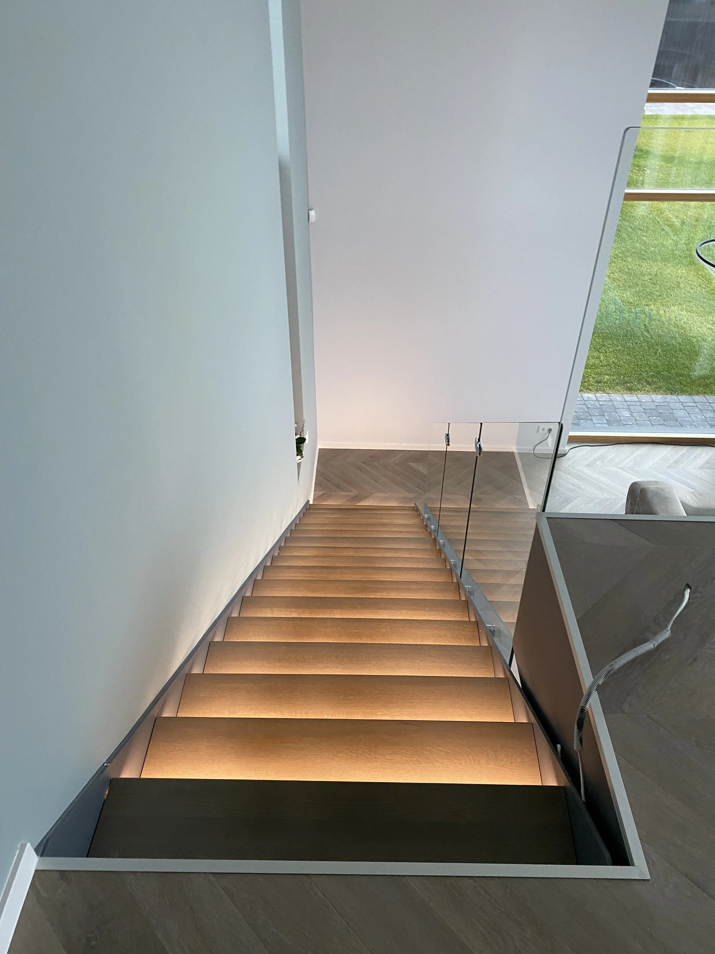 Laiptai su mediniais laipteliais ir šiltu apšvietimu