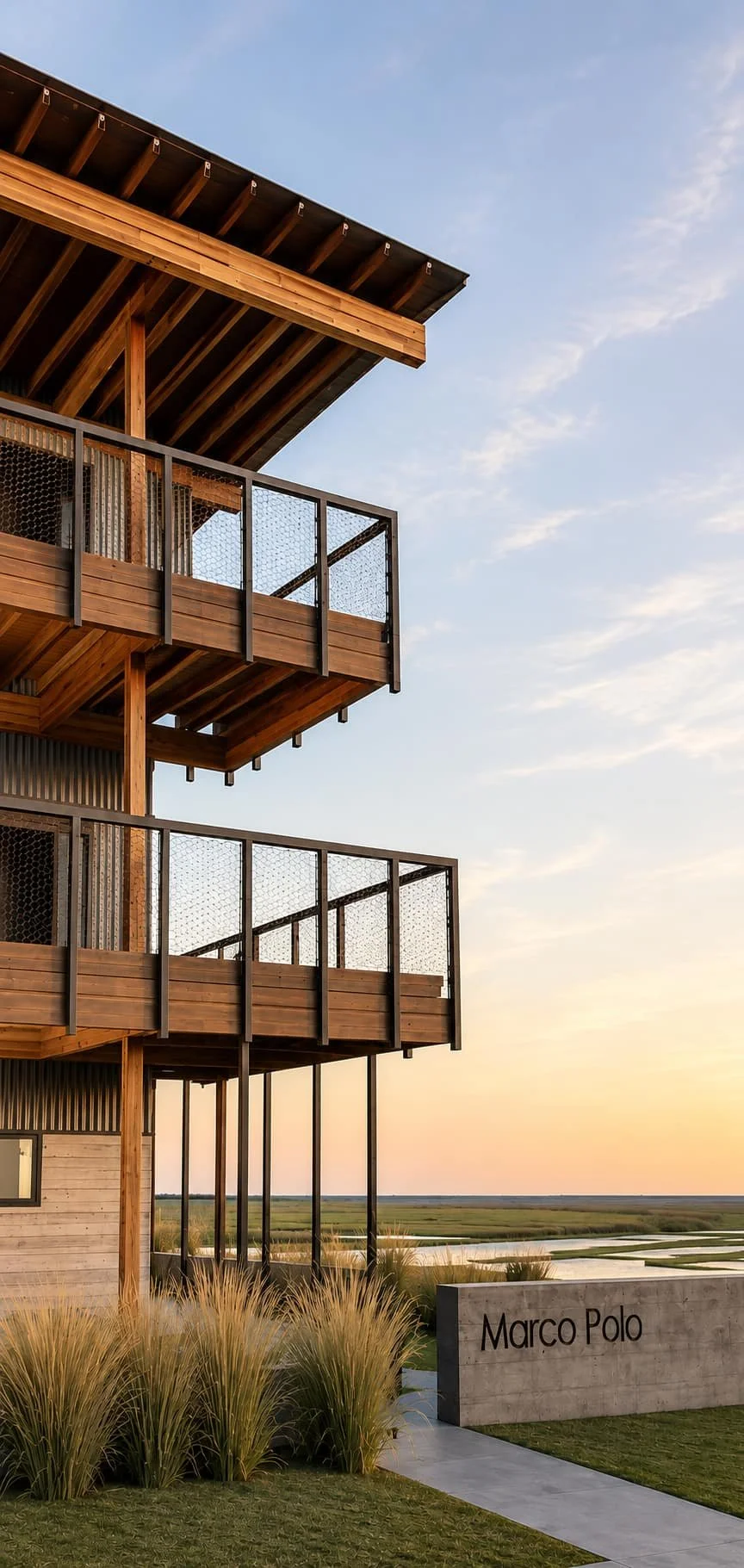 Exterior of a multi-story wooden building with multiple balconies and metal railing, set against a sunset sky with a grassy landscape and a sign that reads "Marco Polo" in the foreground.