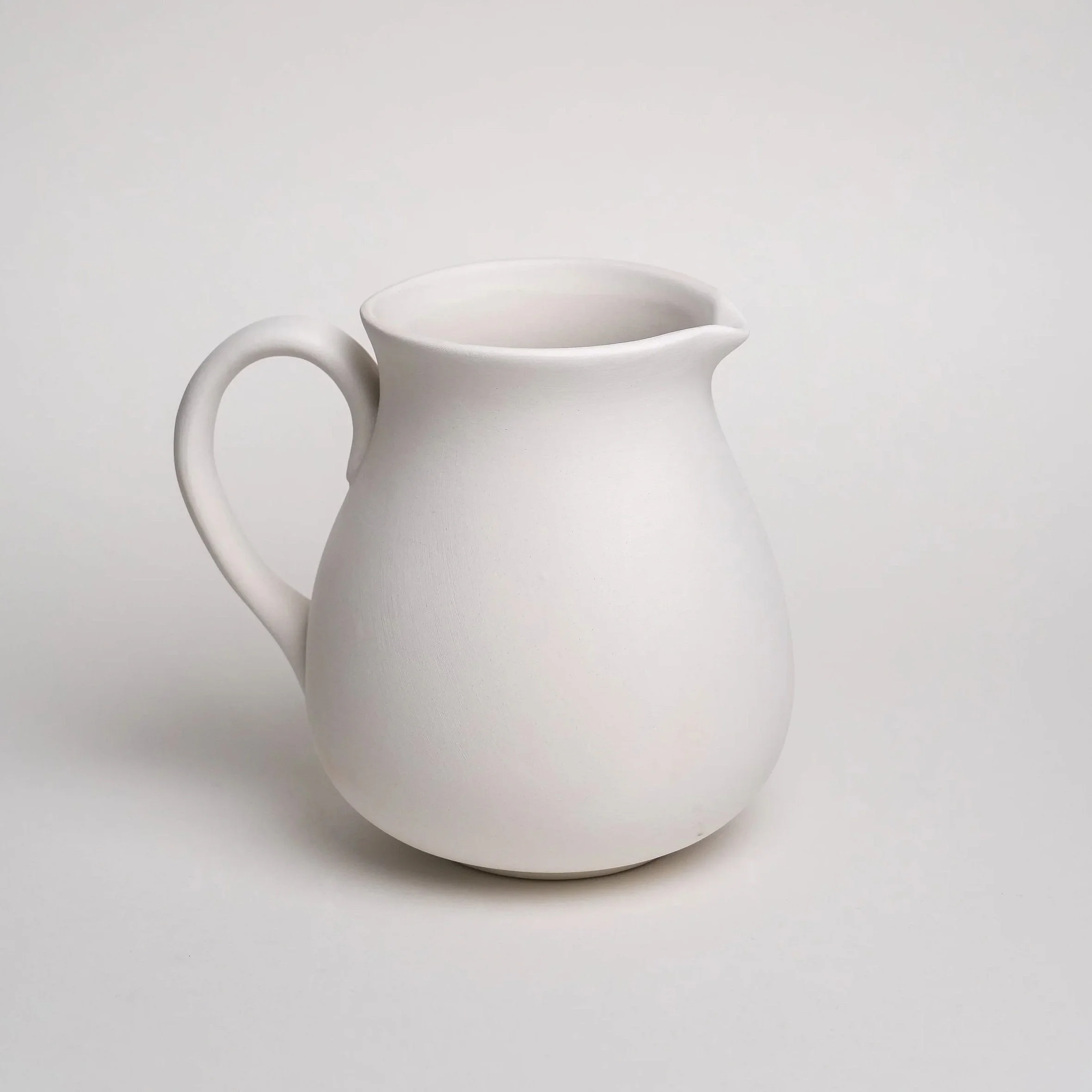 En hvid porcelænskande med håndtag, sat mod en neutral baggrund.