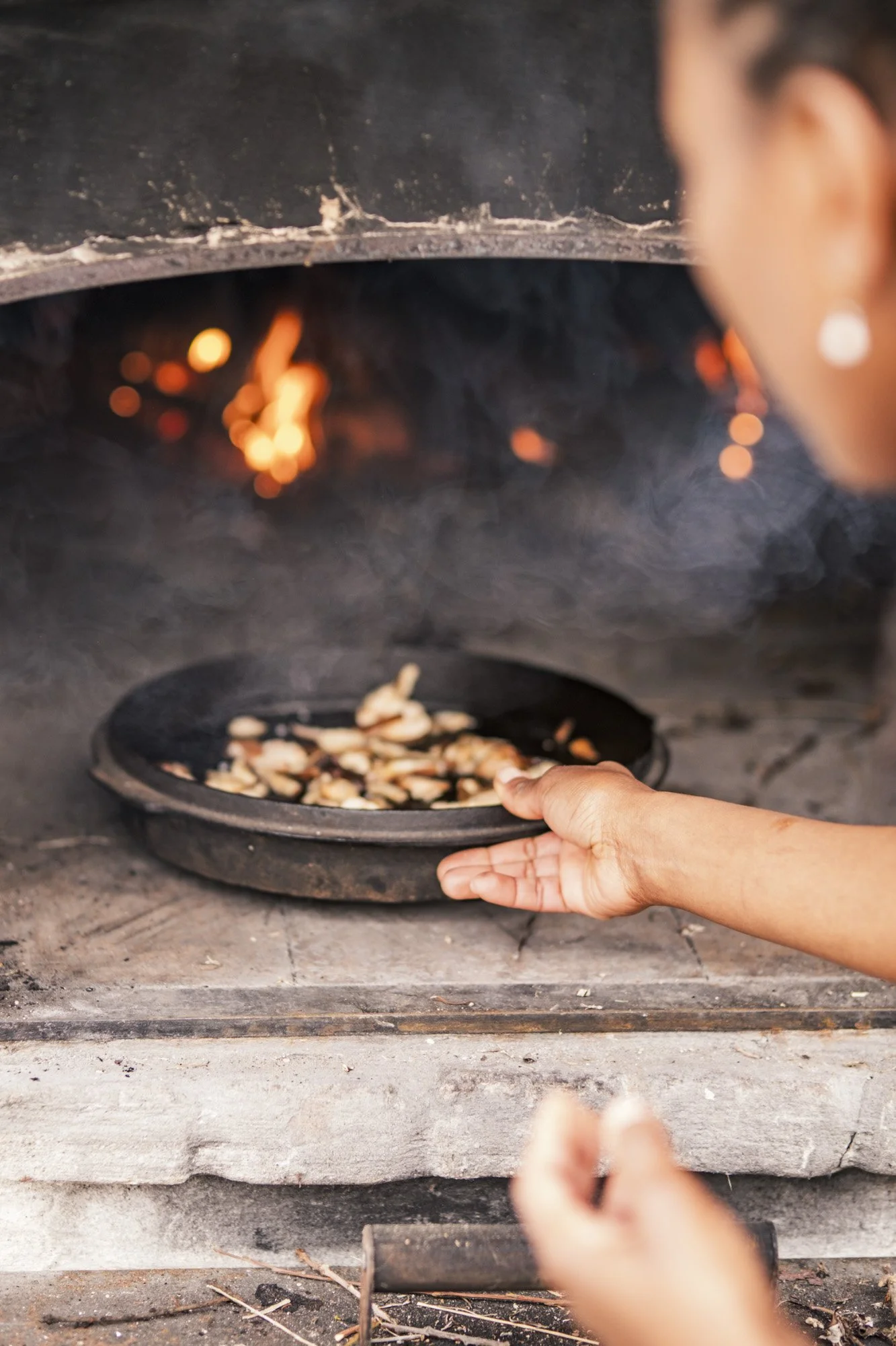 Michel Gonzaga puts the mushrooms in the fire during her workshop cooking with fire