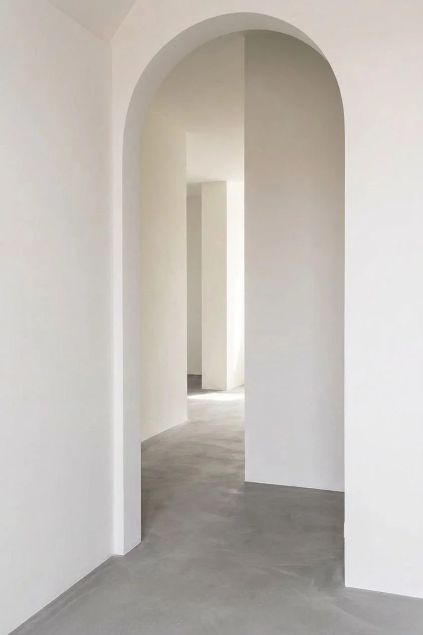 Strak gestucte witte muren met moderne boogdoorgang in minimalistisch interieur, professioneel stucwerk en glad pleisterwerk voor een luxe afwerking door ervaren stukadoor