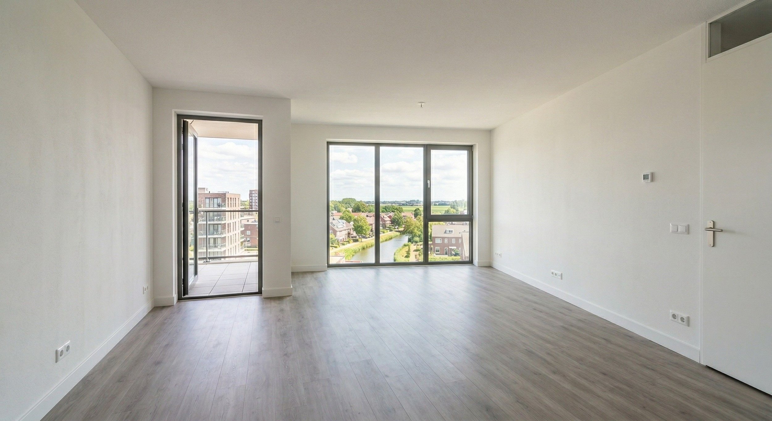 Lichte nieuwbouwwoning met strak gestucte wanden en plafond, glad pleisterwerk en moderne afwerking, ruime woonkamer met grote raampartijen en balkon.