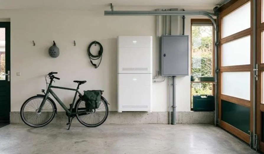 Grote witte thuisbatterij van twee gestapelde modules in een Nederlandse garage, naast de meterkast