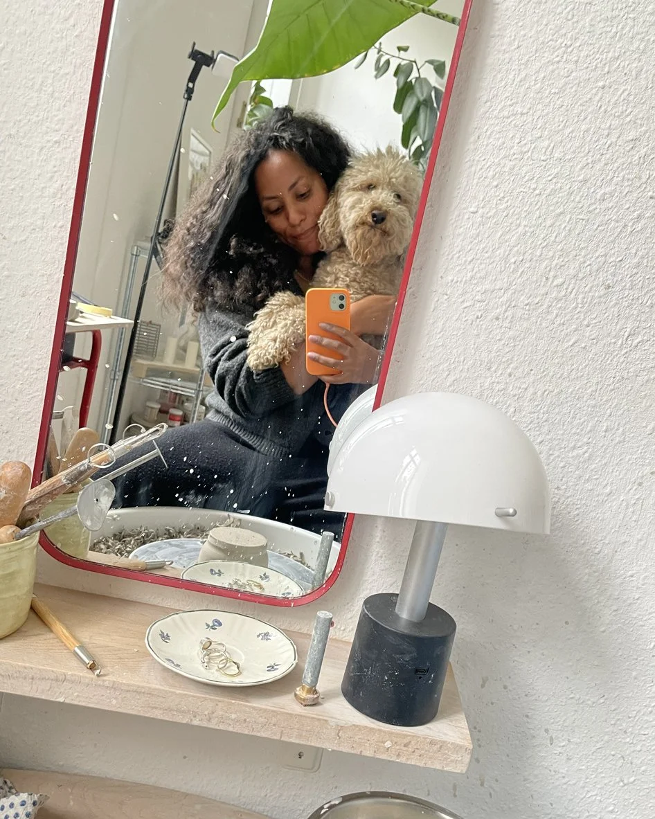 Eine Frau macht ein Selfie mit einem Hund in einem Spiegel vor einer Töpferscheibe.