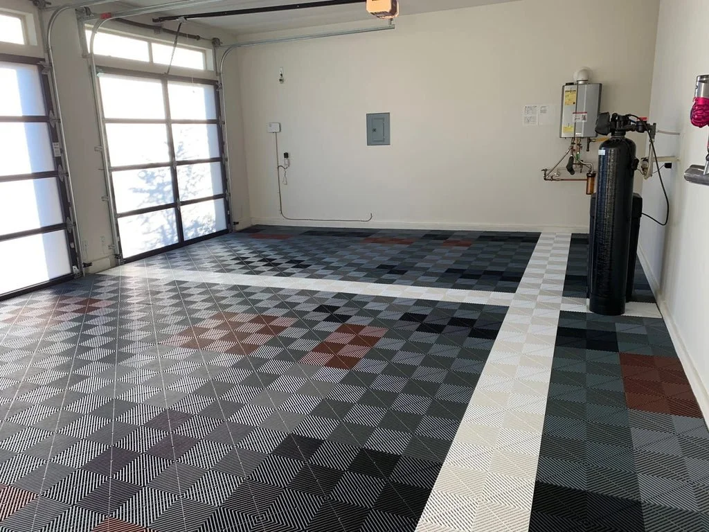 Empty garage with patterned swisstrax tile flooring, a large garage door.