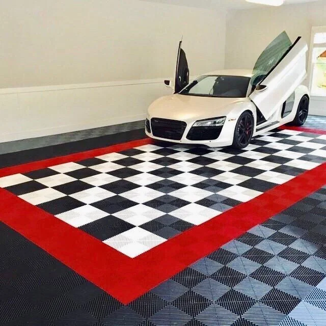White sports car with gullwing doors open parked on a checkered black and white swisstrax floor with red border, inside a showroom or garage.