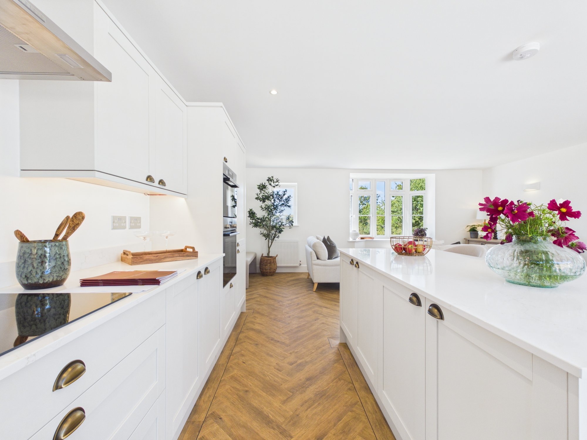 Bright, white kitchen with island, large windows, and pink flowers on the counter.