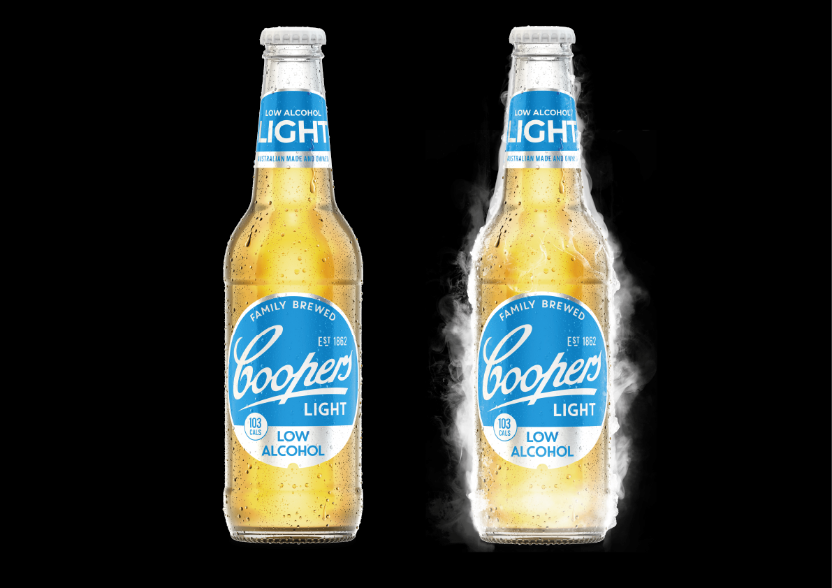 Two glass bottles of Cooper's Light low alcohol beer against a black background, one with condensation and the other emitting vapor.