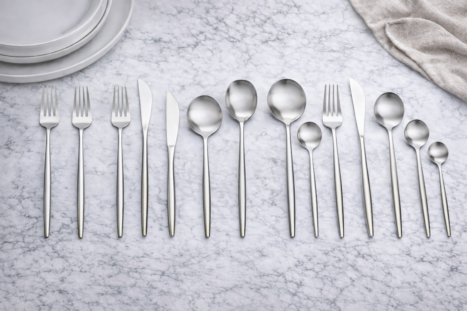 Stainless steel flatware on marble surface.png