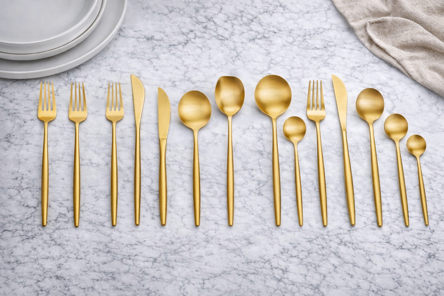 Matte gold cutlery on marble surface.png