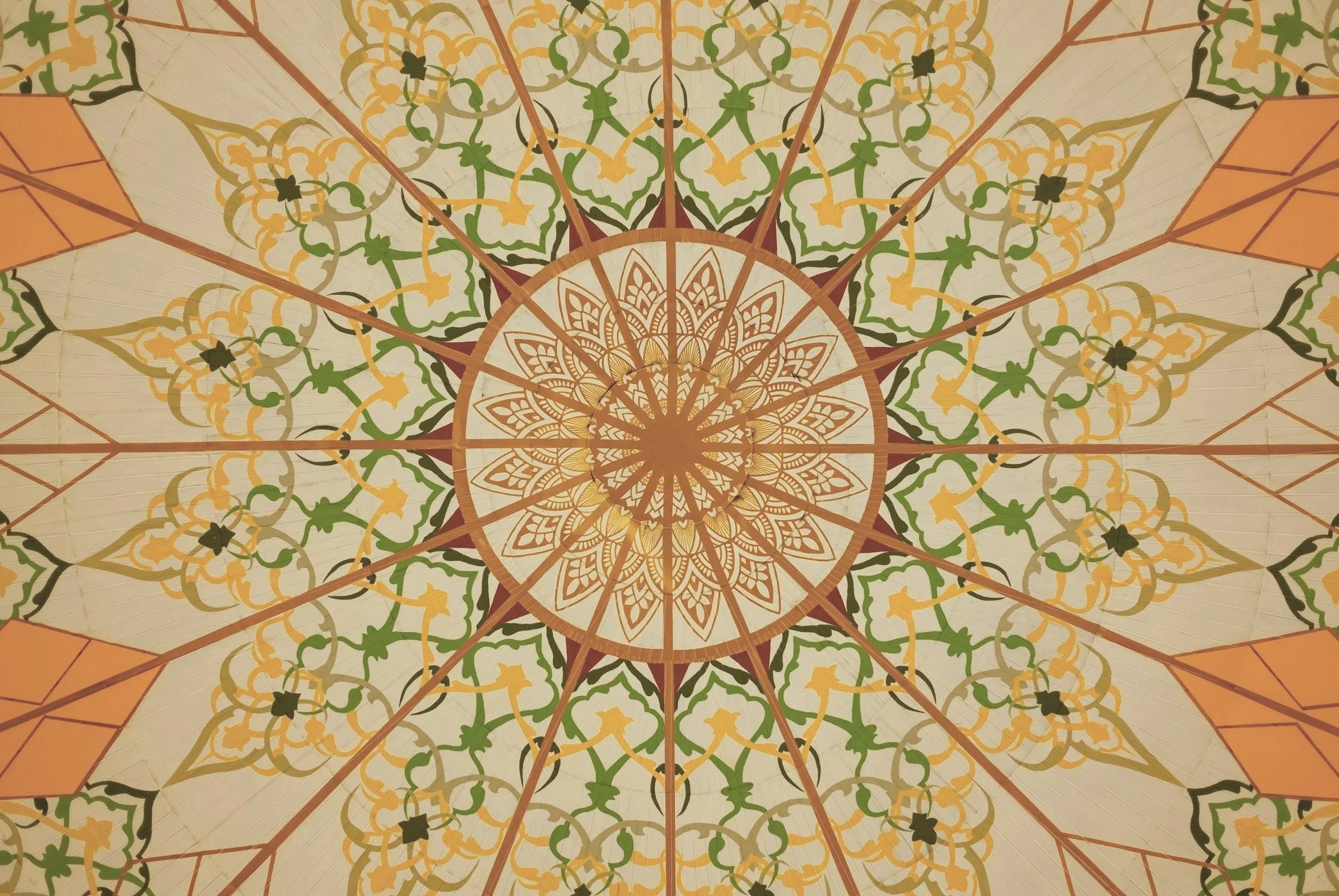 Detaljerad, färgglad takdekoration med geometriska mönster i beige, grönt, gult, svart och orange.