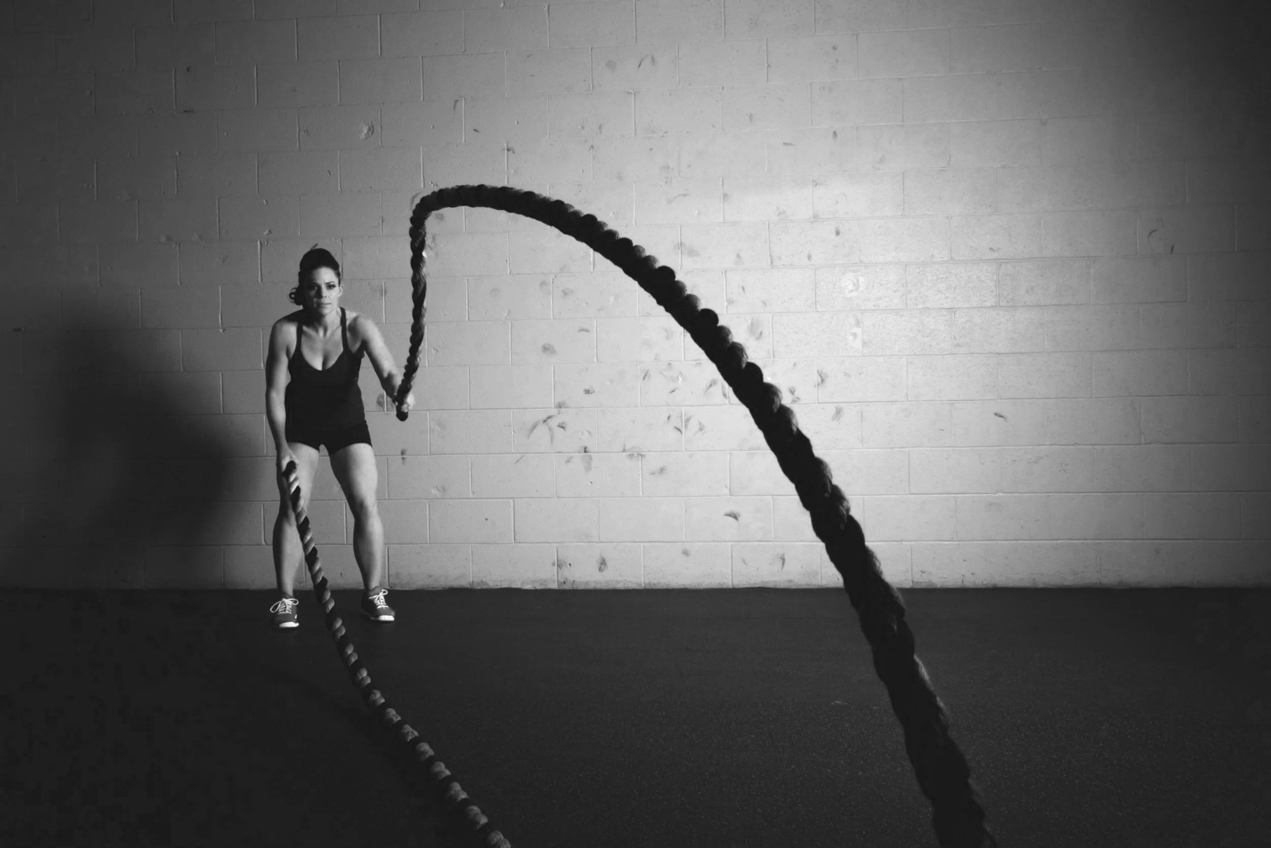 A woman engaging in battle ropes workout in a gym.