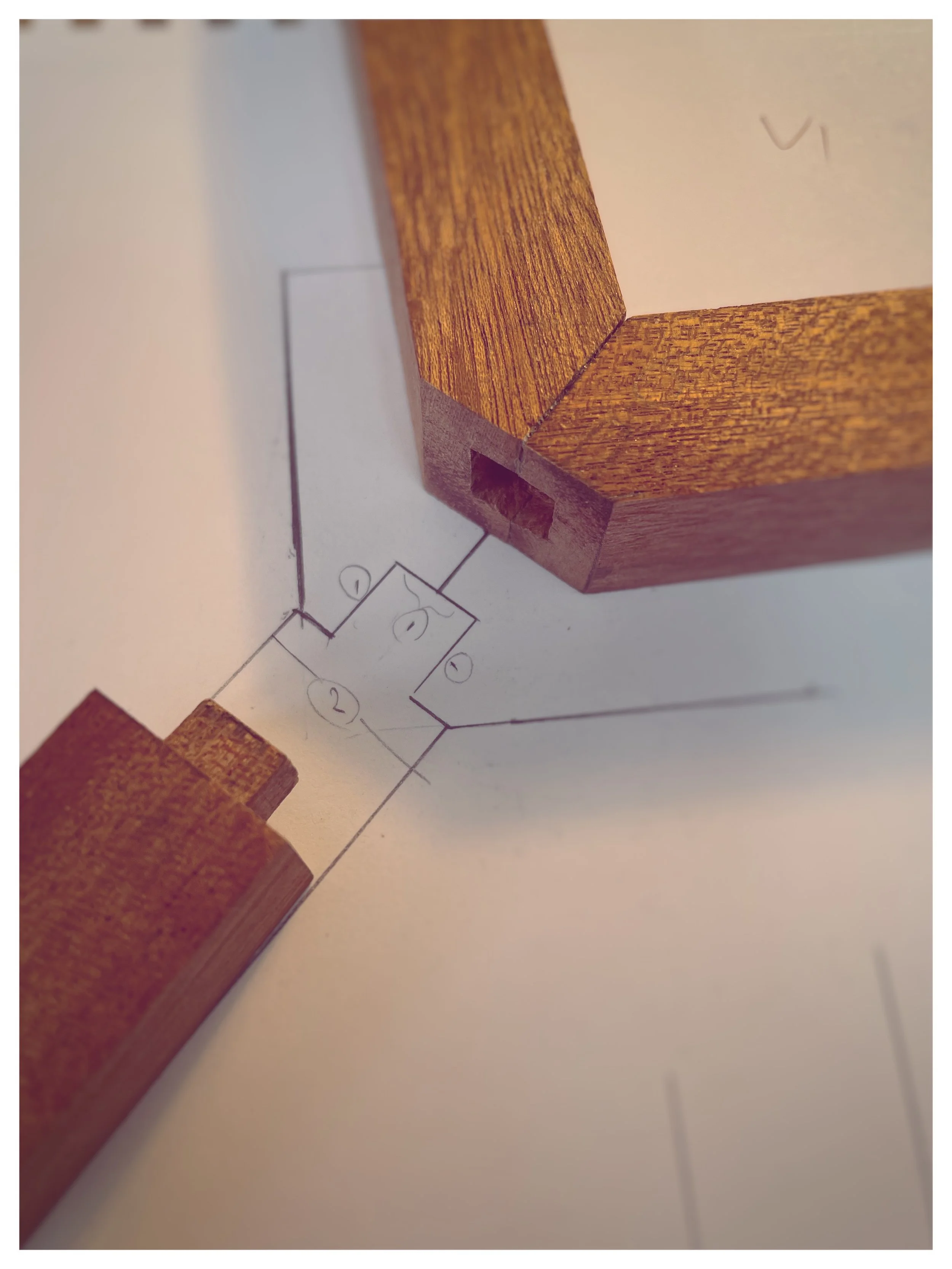 Close-up of corner of wooden furniture or object on top of a paper with a drawing or schematic diagram.