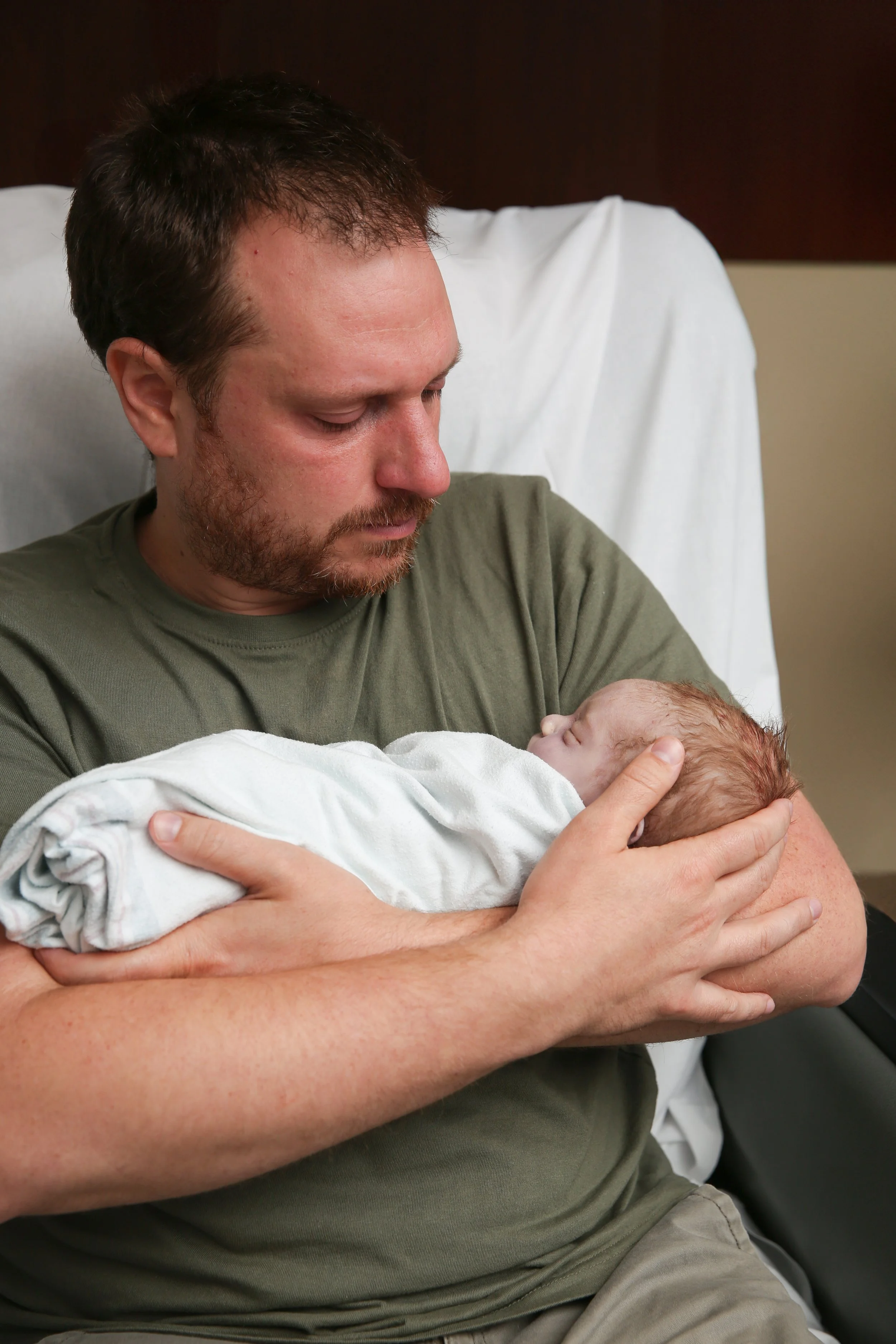 A man holding a newborn baby in a hospital room.