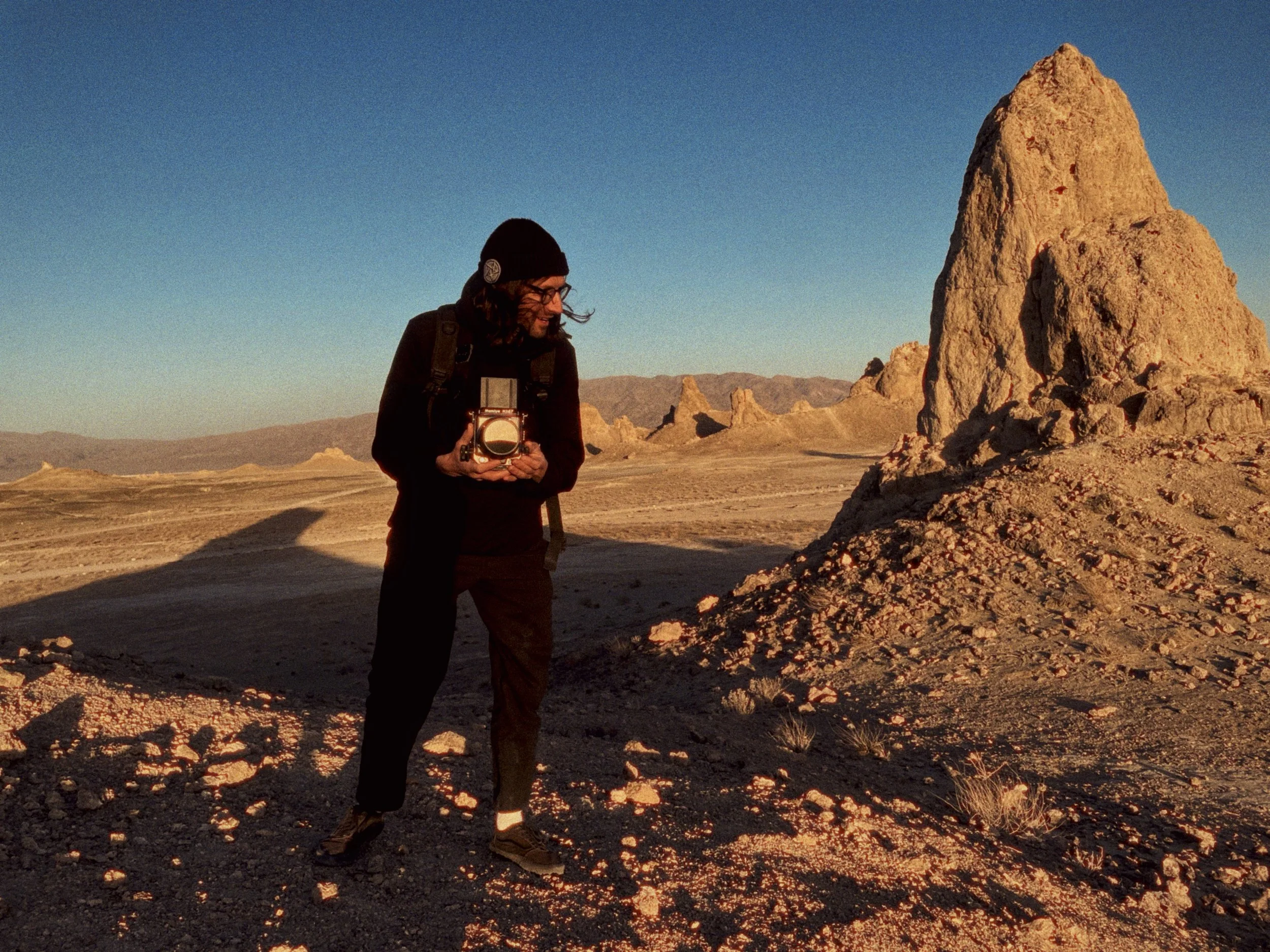 A portrait of photographer Dan Medhurst holding his Mamiya RZ 67 120 camera, shooting on location in the desert.