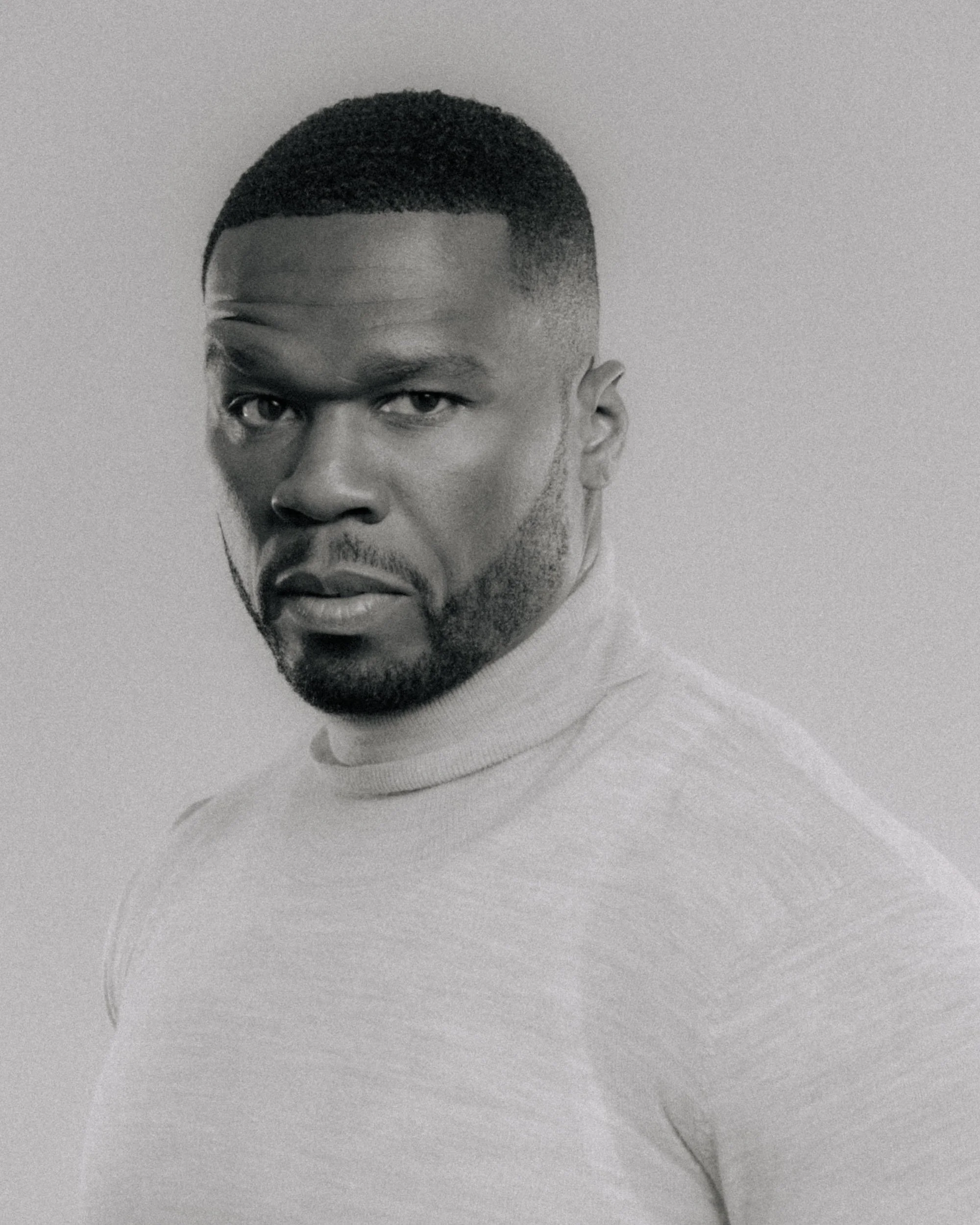 A black and white portrait of a young man with a short haircut, serious expression, and wearing a light-colored shirt.