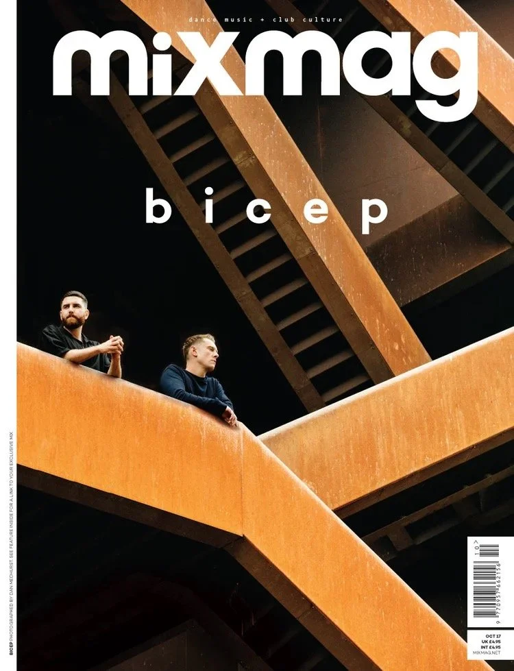 The cover of Mixmag magazine featuring two people standing on an orange stairway with wooden railing, in front of angular architectural elements.