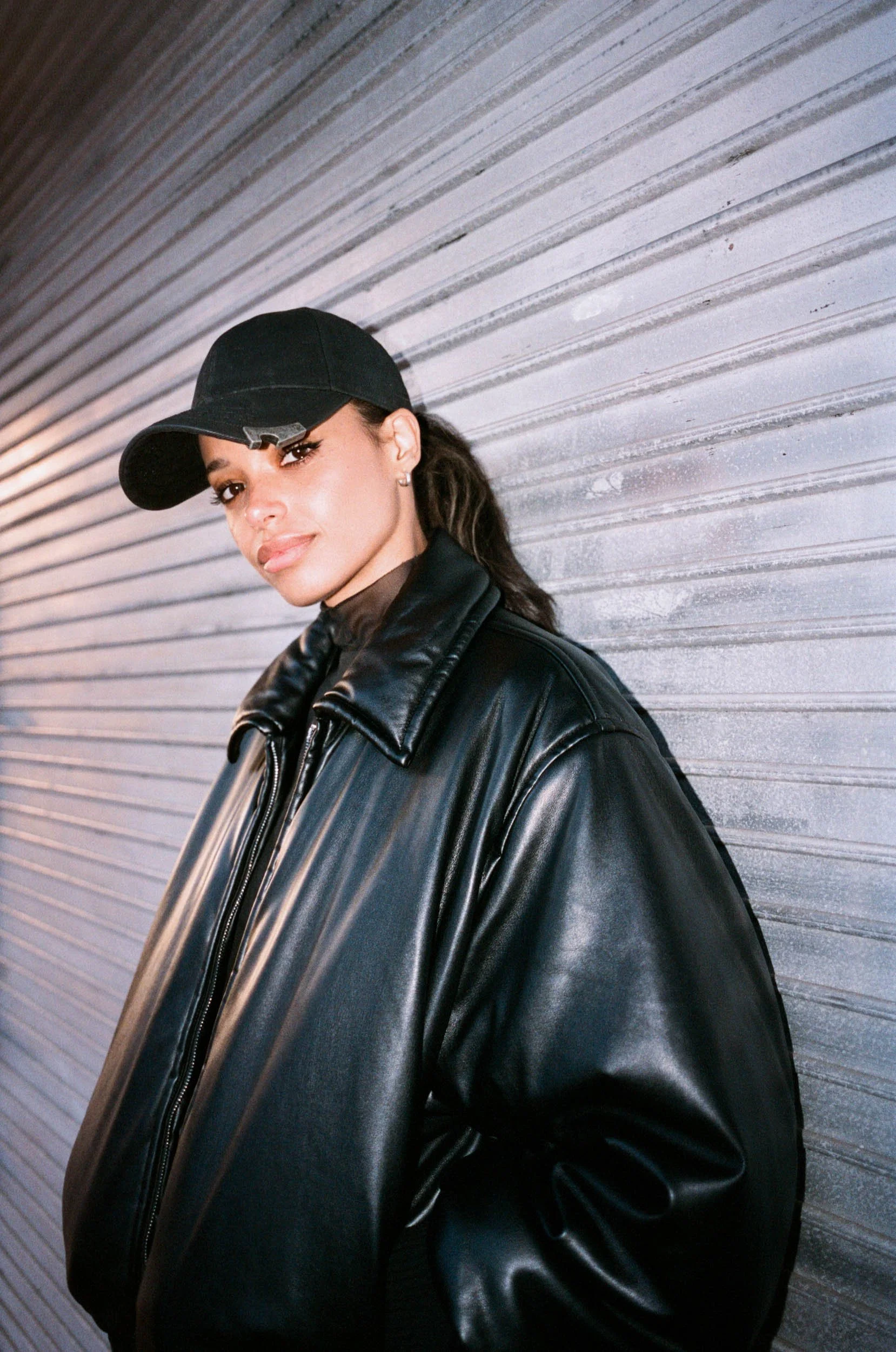 Linska wearing a black baseball cap and a black leather jacket. Photographed by Dan Medhurst.