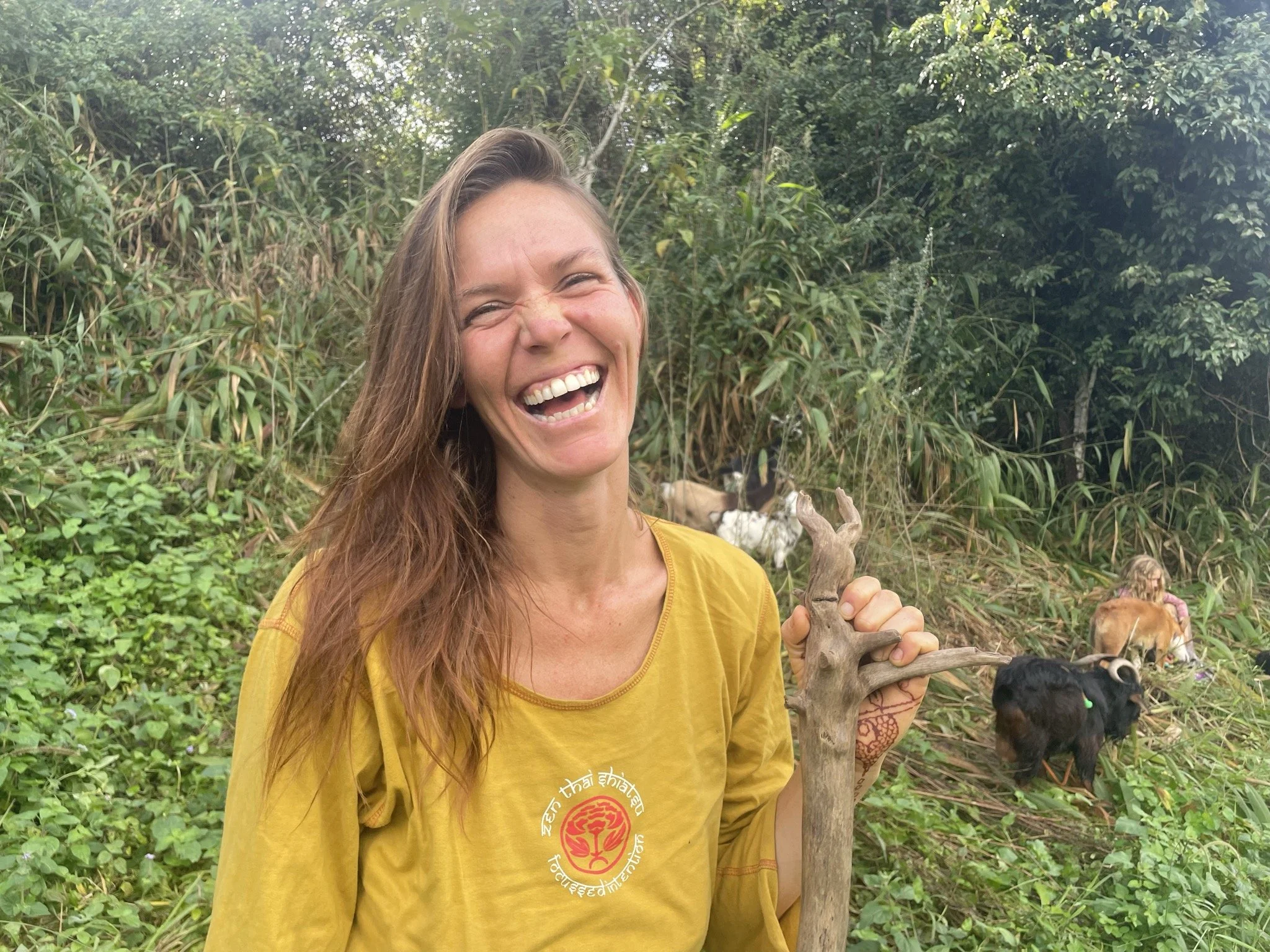 Ashleigh Hart, laughing while walking the land on her daily Goat walk in her Golden Earthy Zenthai Shirt.