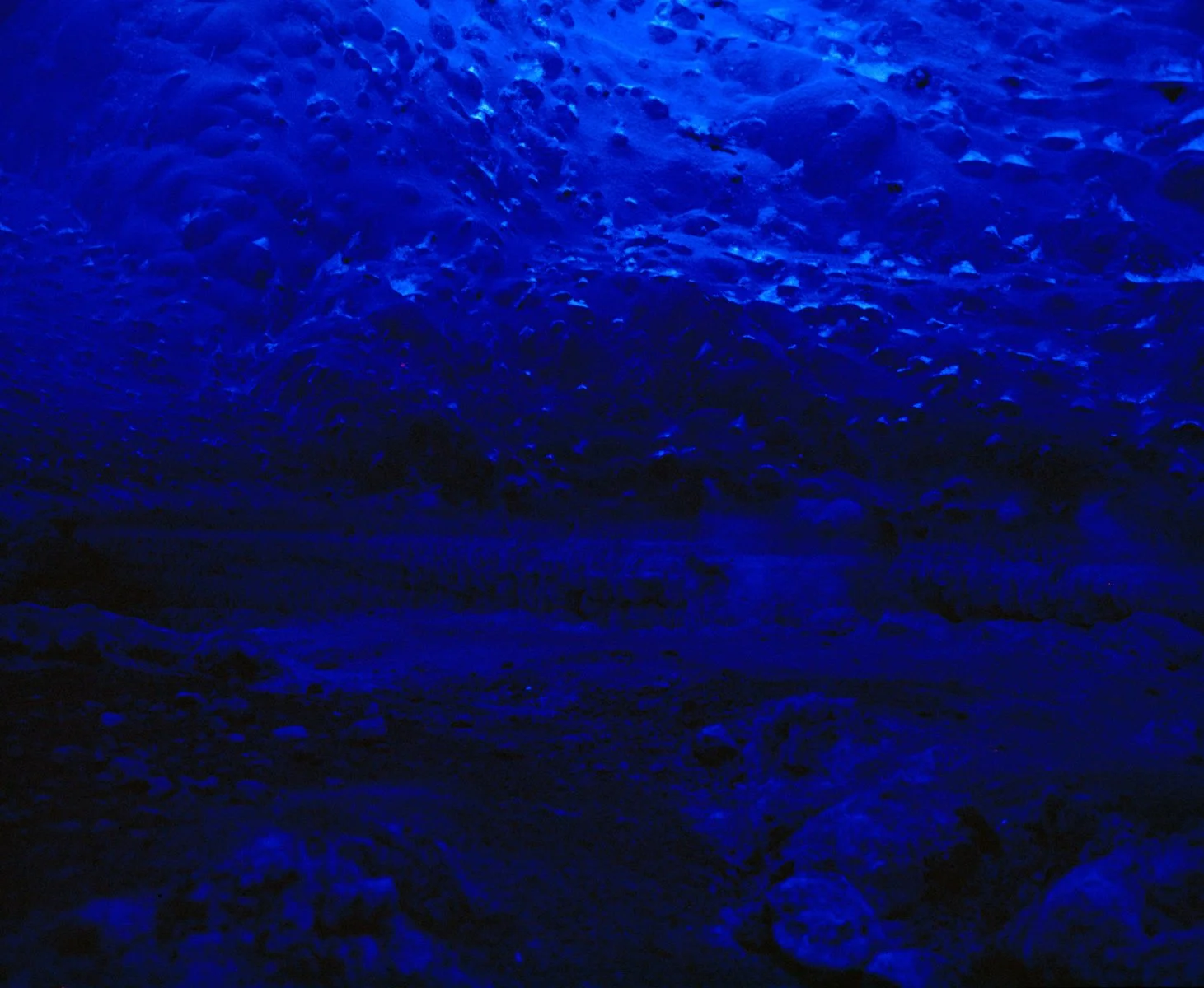 Close-up of foamy ocean waves illuminated in deep blue lighting