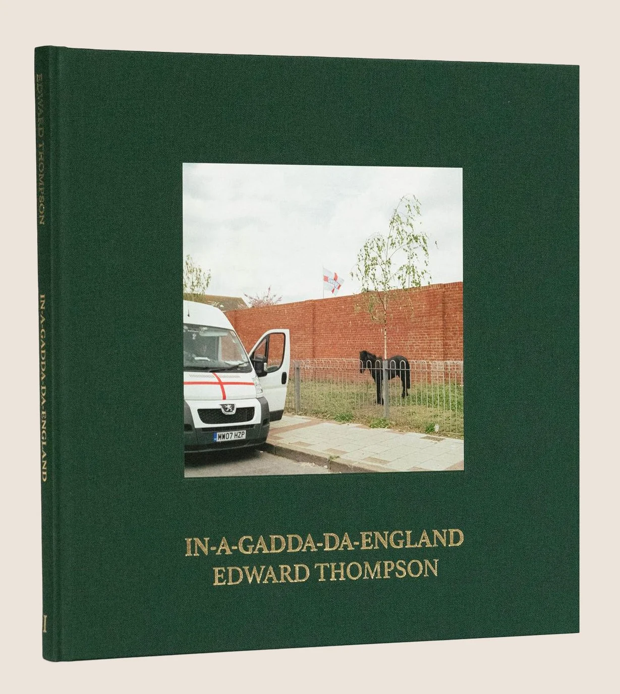 Book titled 'In-a-Gadda-Da-England' by Edward Thompson with a cover photo of a small white van parked beside a sidewalk, an iron gate, a tree, and a brick wall in a suburban area.