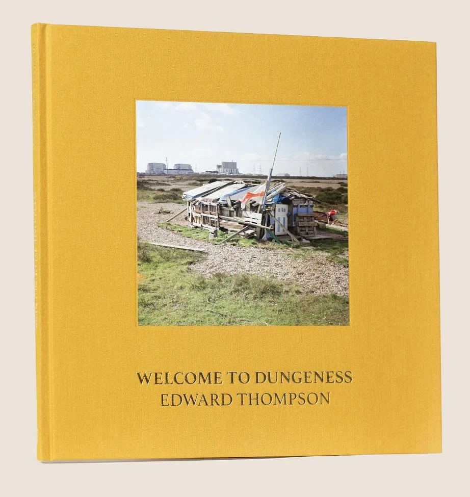 Yellow book titled 'Welcome to Dungeness' by Edward Thompson, featuring a photo of a dilapidated shack in an open field on the cover.