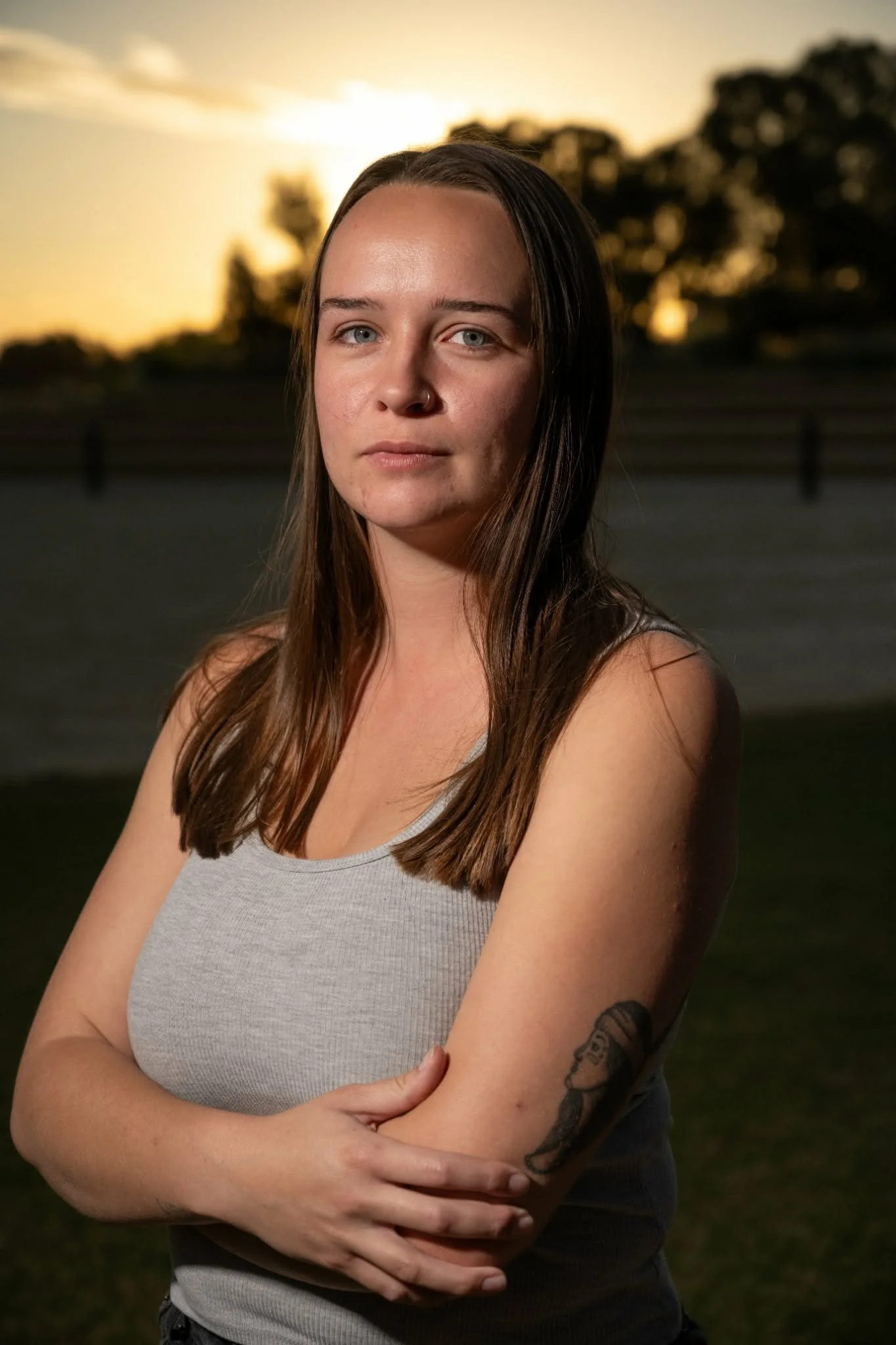 Young Aboriginal woman standing with arms crossed at sunset.