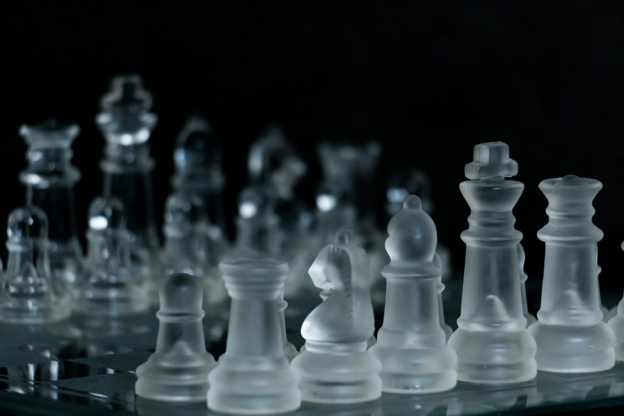 Glass chess pieces arranged on a board, representing strategic thinking and planning