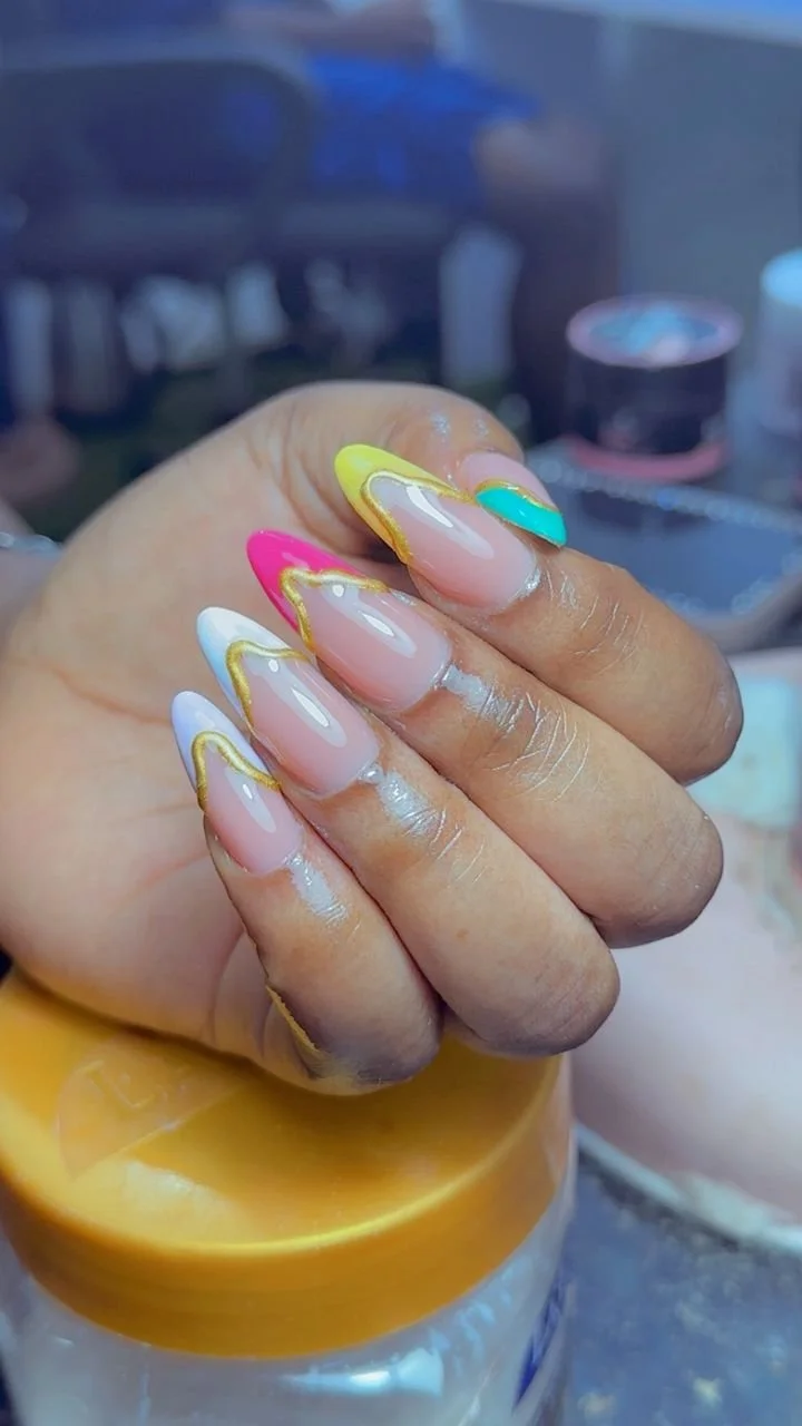 Close-up of a hand with freshly done manicured nails in pastel colors with gold accents.