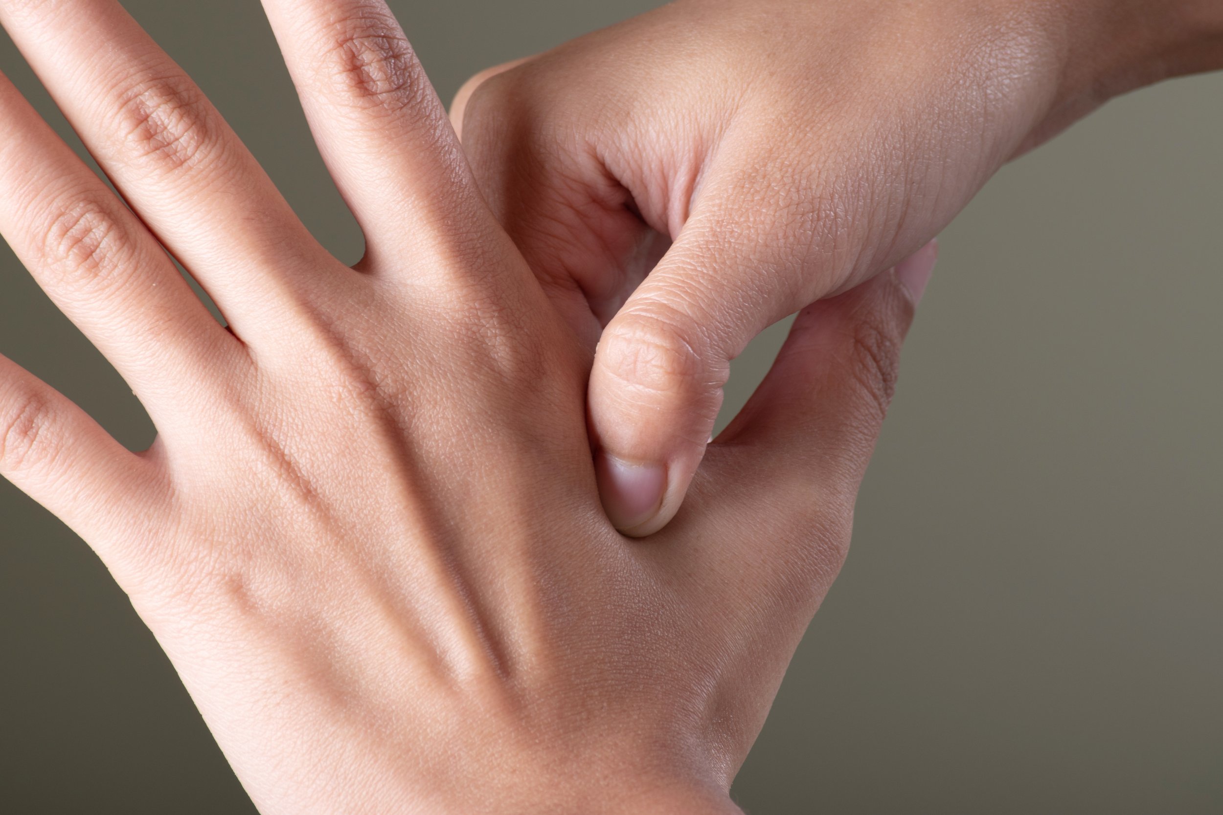 Nahaufnahme von zwei Händen, die einen Handschlag machen, vor einem neutralen Hintergrund.