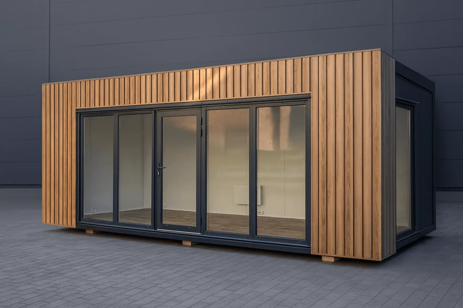 Een moderne kleine gebouw met grote glazen schuifdeuren en houten gevelbekleding, geplaatst op een bestrate ondergrond.