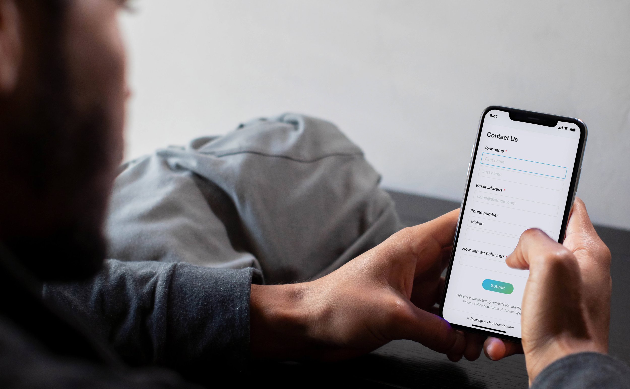 Person holding a smartphone with a contact form on the screen.