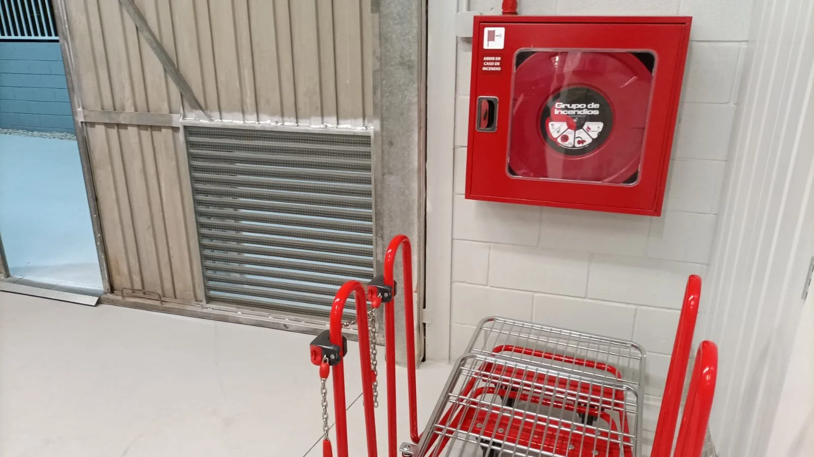 Carrito de supermercado y caja de extintor de incendios en interior de tienda.