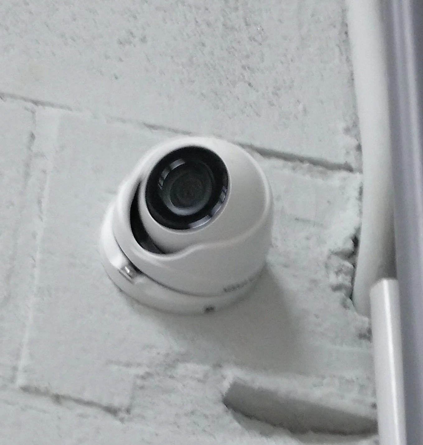 Cámara de seguridad fija instalada en la pared de azulejo blanco.